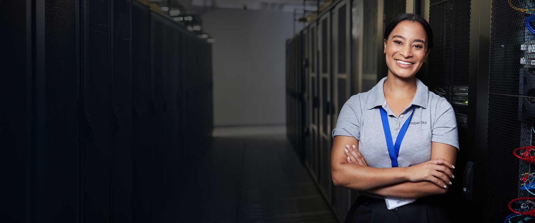 A Proper Sky engineer in a server aisle, arms crossed, smiling